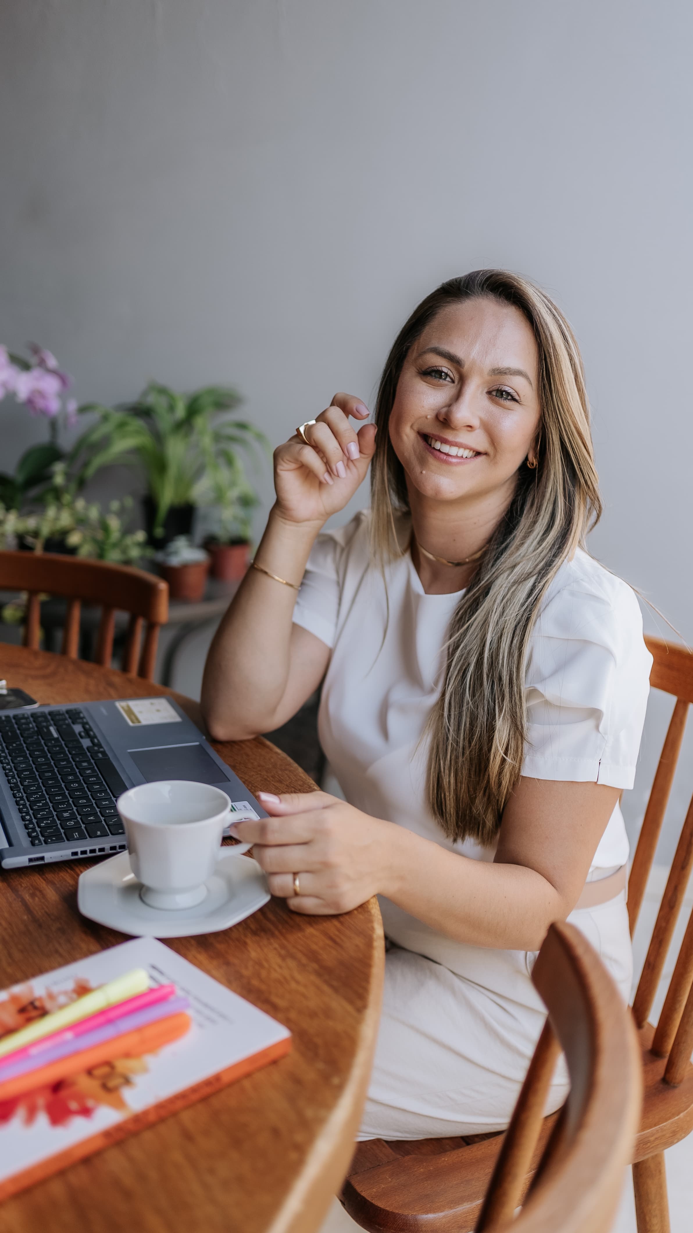 Cinthia Vallim trabalhando em ambiente acolhedor, com notebook e café